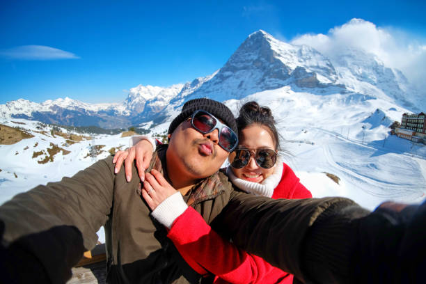 junge paar touristen selfie mit handy in der nähe von bahnhof kleine scheidegg, entlang der bahn von interlaken zum jungfraujoch (3.466 m). im tageslicht ati schweiz - jungfrau train winter wengen stock-fotos und bilder