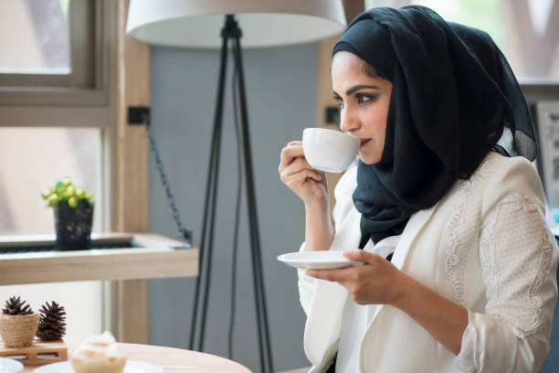 arabische frauen hijab halten und trinken kaffeetasse in der cafeteria sitzen. - religiöse kleidung stock-fotos und bilder