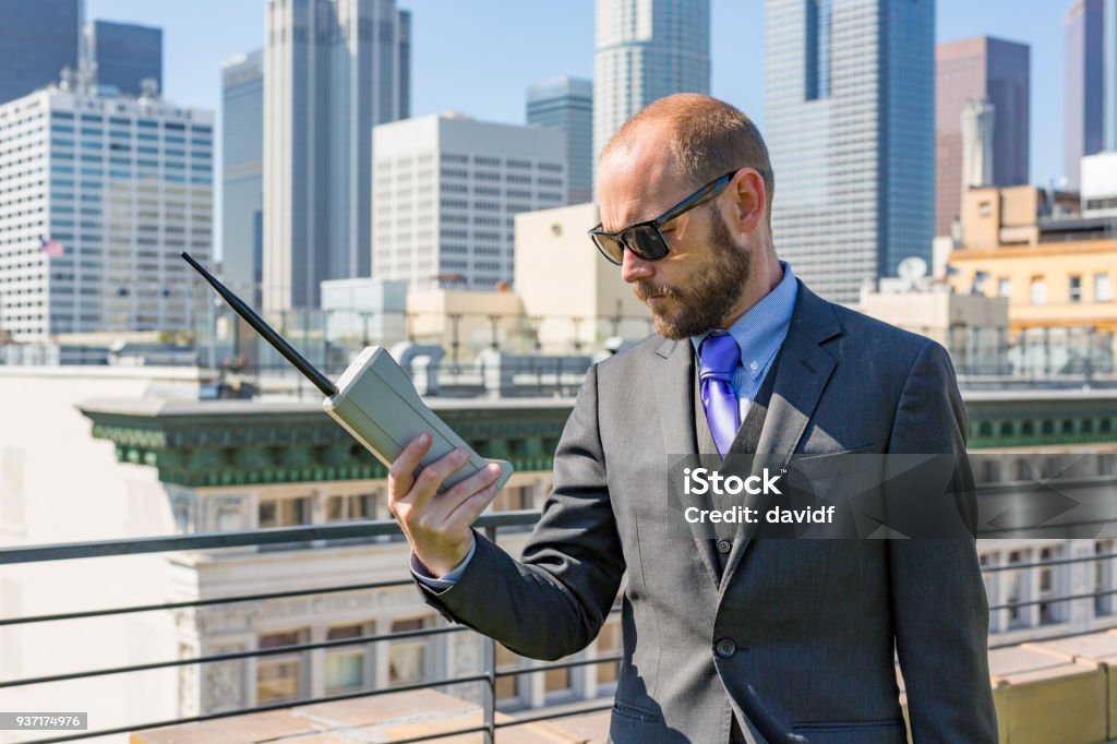 Rooftop Businessman With a Retro Mobile Phone Business man on a rooftop using an old fashioned retro mobile phone 1990-1999 Stock Photo