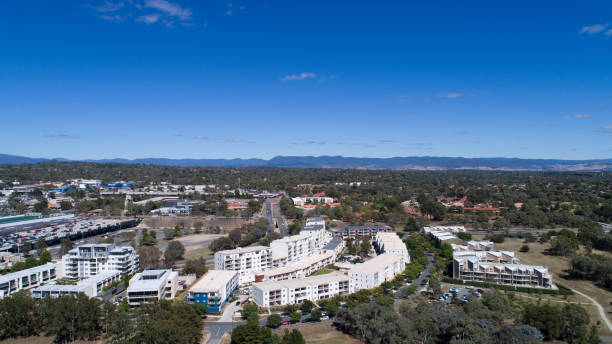 Aerial of suburban townhouses in Belconnen High aerial viewpoint photographed by a DJI Phantom 4pro, looking towards suburban townhouses, some commercial premisses in the background such as Officeworks and Coles, many cars parked and moving around a few people not recognisable in the distance. Photographed on a nice sunny day. belconnen stock pictures, royalty-free photos & images