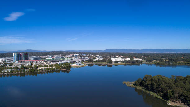 Aerial from Lake Ginninderra towards Belconnen town centre High viewpoint photographed by a DJI Phantom 4pro, looking towards Belconnen town centre with a slight reflection on lake, many cars parked on a nice sunny day. belconnen stock pictures, royalty-free photos & images