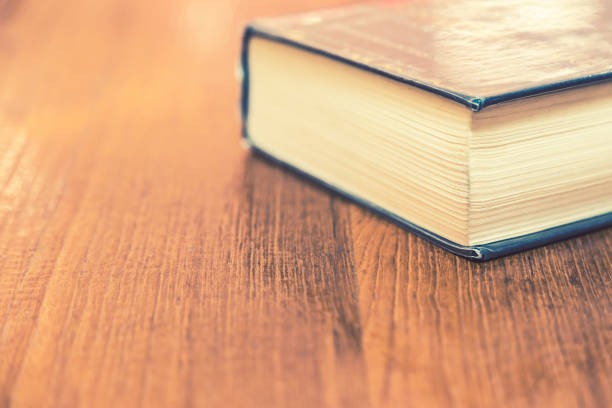 istock Old thick hard cover book on wooden table, room for text or copyspace, selective focus 937182632