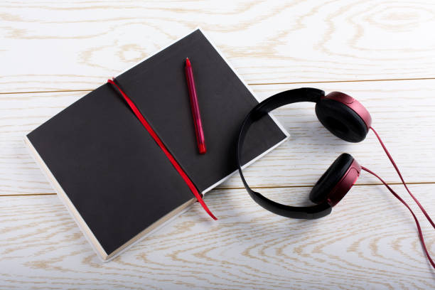 istock Pen, notebook and headphone on wooden texture 937193586