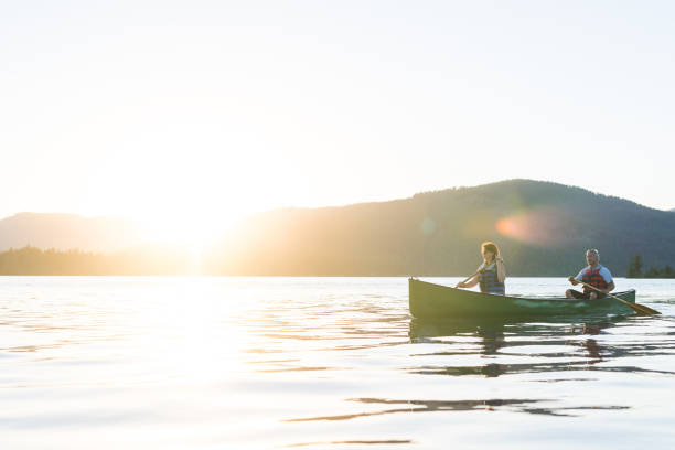 istock Older couple canoe together on a lake at sunset 937207052