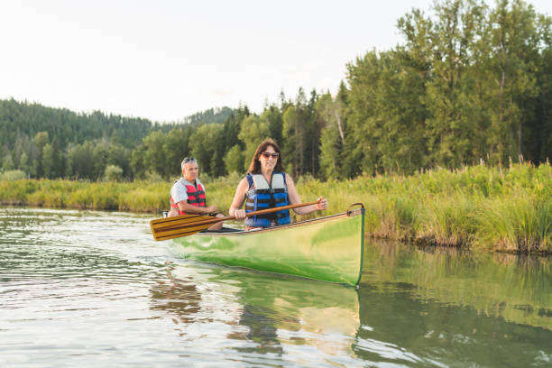 istock Senior couple canoeing together around a forested lake. 937207064