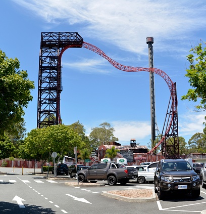 Coomera, Queensland, Australia - January 9, 2018. Exterior view of Buzzsaw and Tower of Horror ride attractions at Dreamworld theme park, taken from parking lot outside of the park, with cars.