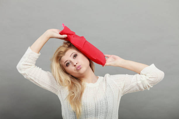 istock Woman holding red hot water bottle on head 937217434