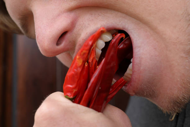 Detail of mouth biting peppers.