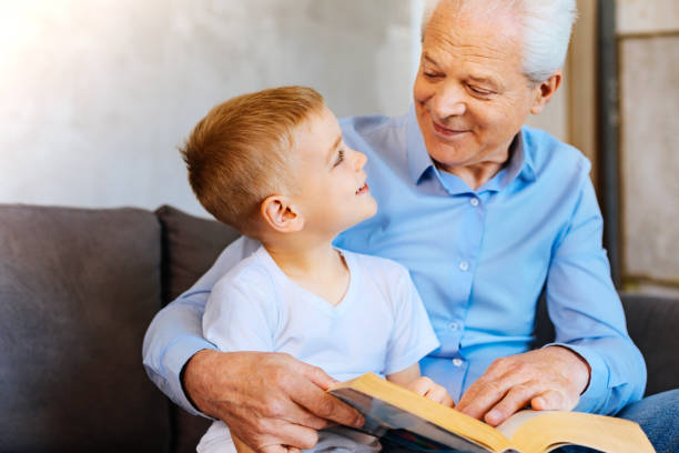 istock Cheerful nice boy reading a book with his grandfather 937221918