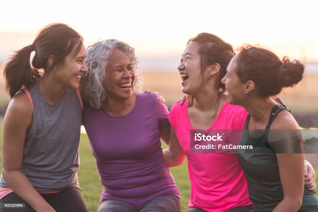 Cuatro mujeres étnicas riendo juntos después de un entrenamiento al aire libre - Foto de stock de Sólo mujeres libre de derechos