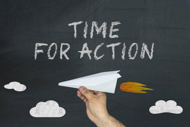istock Hand holding paper airplane and text written on blackboard: Time for action 937222364