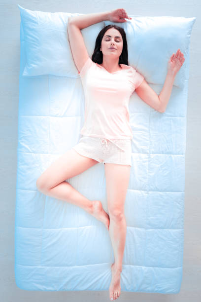 Raise your hands. Attractive female person keeping smile on her face and taking comfortable pose while lying on her bed