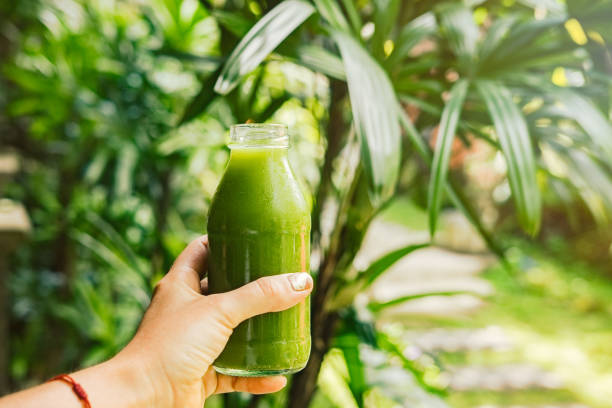 istock Woman's hand holding a bottle with green juice 937244600