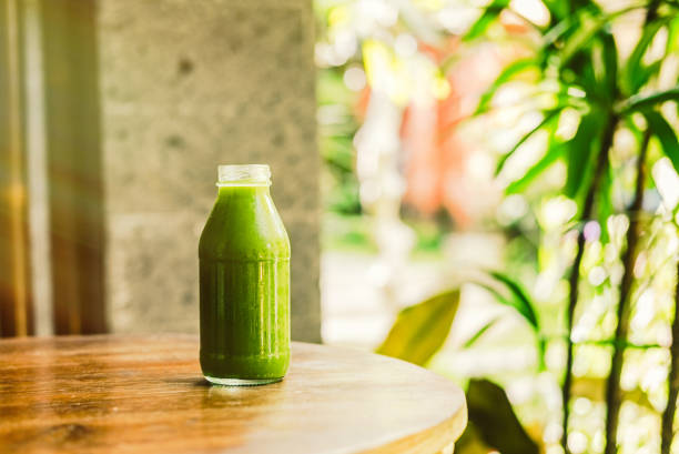 Bottle with green juice, nature background, sunny morning. Healthy eating, detoxing, juicing, fasting, body cleancing concept