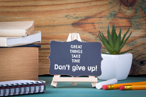 Great things take time Don't give up. small wooden board with chalk on the table