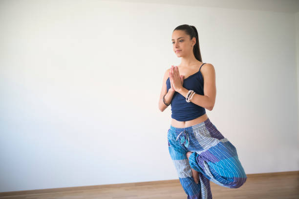 Beautiful, young woman doing tree yoga position.