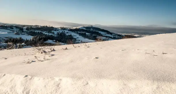 Ochodzita hill with dispersed settkement of Koniakow village bellow in Beskid Slaski mountains in Poland during winte day with snow and blue skyr