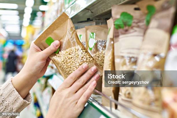 Manos Con Piñones De Envasado En La Tienda Foto de stock y más banco de imágenes de Orgánico - Orgánico, Alimento, Supermercado