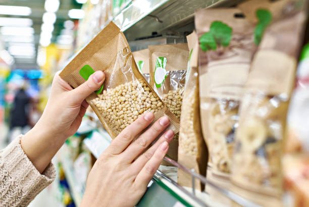 Hands with packaging pine nuts in store Buyer hands with the packaging of pine nuts in the store organic food stock pictures, royalty-free photos & images