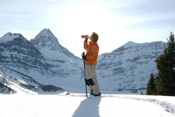 Snowcapped peaks behind. Orange ski jacket. Mt Assiniboine Provincial Park, BC
