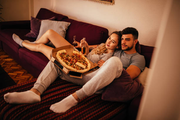 istock Young hipster couple watching TV with beer and pizza 937261208
