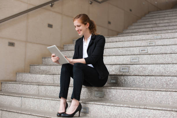 istock Happy businesswoman using digital tablet on stairs 937262118