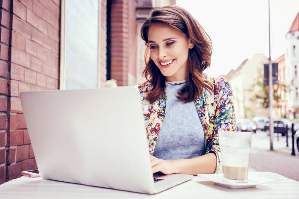 istock Beautiful woman working on laptop at outdoors cafe 937262284