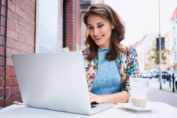 istock Beautiful young woman typing on laptop during coffee break at outdoors cafe 937263316