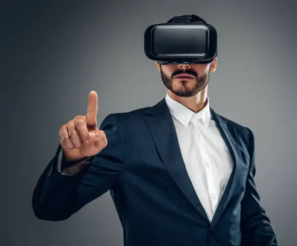 Bearded male dressed in a suit with virtual reality glasses on his head.