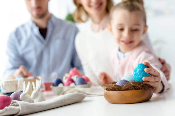 istock Child putting Easter egg in nest by her family 937269198