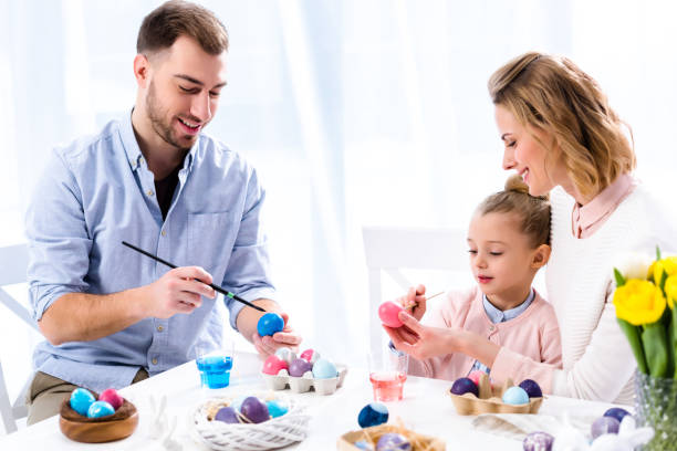 istock Family coloring Easter eggs with painting brushes 937270464