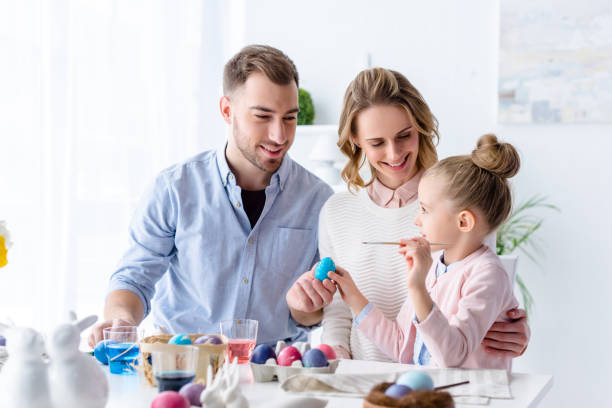 istock Parents and daughter painting Easter eggs 937274558