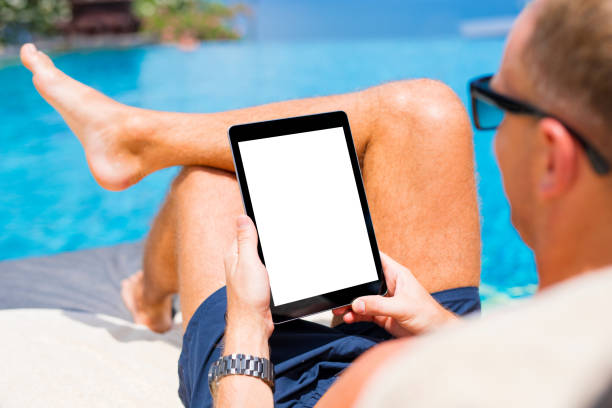 istock Man using tablet on vacation by the pool. Digital tablet mockup, vertical screen orientation. 937274840