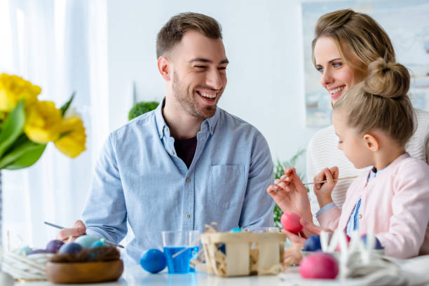 istock Smiling family having fun on Easter by table with painted eggs 937274914