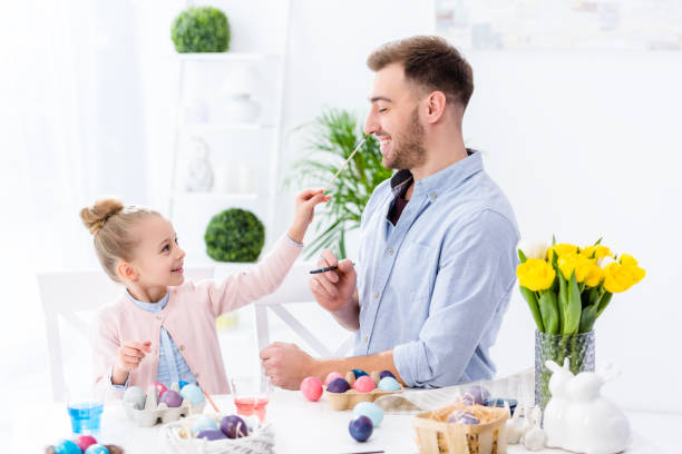 istock Young man and child girl painting Easter eggs 937275592