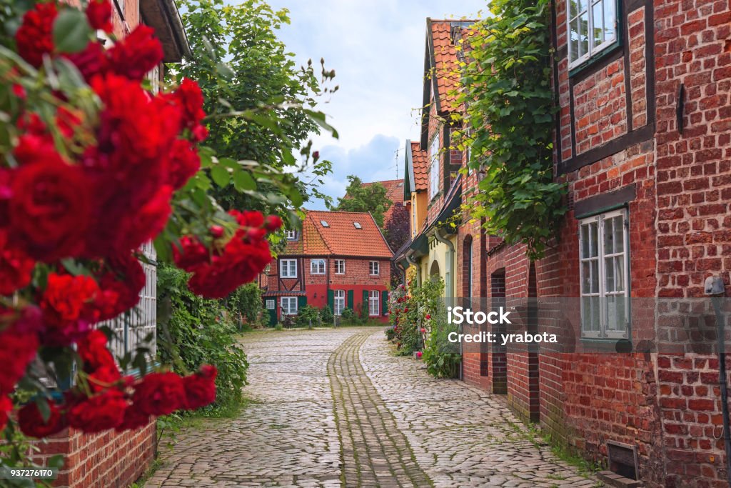 Beautiful cozy street of the old town. Beautiful cozy street of the old town of Luneburg in Germany. A street in a small German city, cozy apartment houses, lots of greenery, flowers, cobblestone pavement. Quiet and calm town. Lüneburg Stock Photo
