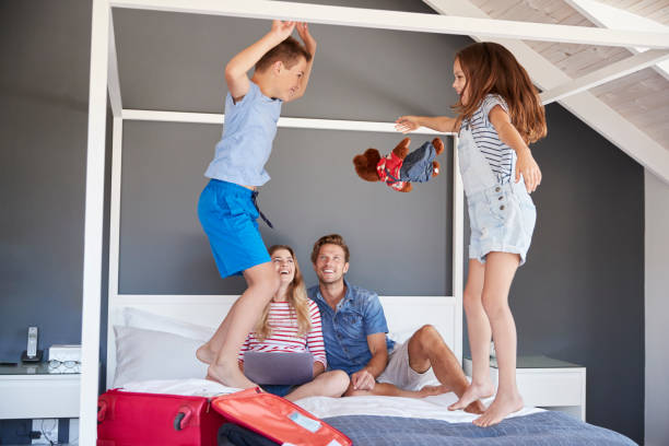 istock Excited Children Jump On Bed As Parents Pack For Vacation 937278424