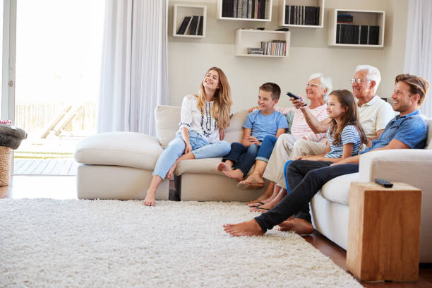 istock Multi Generation Family Sitting On Sofa At Home Watching TV 937278632