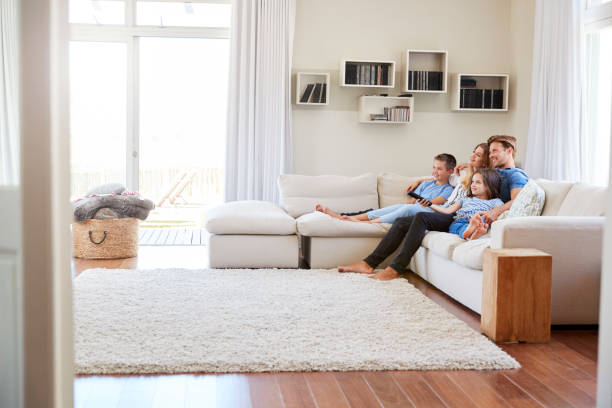 familie sitzt auf sofa zu hause vor dem fernseher zusammen - zimmer bildschirm stock-fotos und bilder