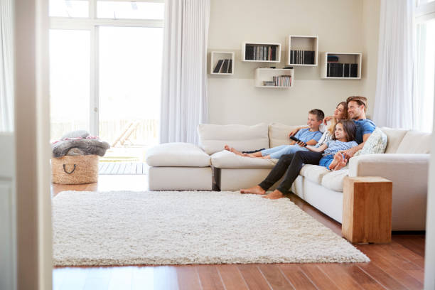 famiglia seduta sul divano a casa a guardare la tv insieme - domestic life young family family child foto e immagini stock