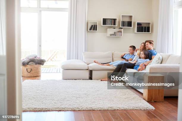 Foto de Família Sentada No Sofá Em Casa Assistindo Tv Juntos e mais fotos de stock de Família