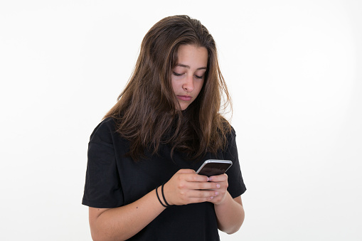 Happy beautiful young woman with long curly hair holding mobile phone over white background