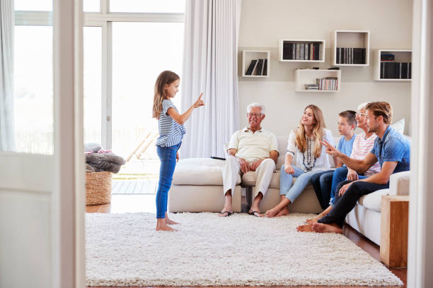 Multi Generation Family Sitting On Sofa At Home Playing Charades Multi Generation Family Sitting On Sofa At Home Playing Charades pantomime stock pictures, royalty-free photos & images