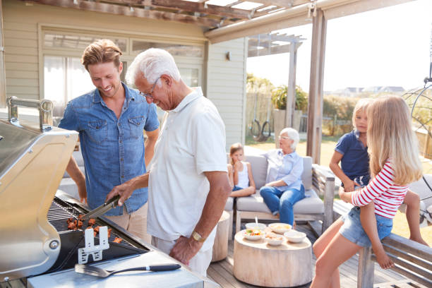 Multi Generation Family Enjoying Cooking Barbecue At Home Multi Generation Family Enjoying Cooking Barbecue At Home staycation stock pictures, royalty-free photos & images