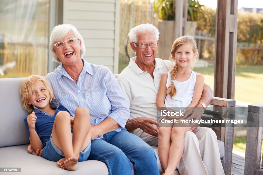 Grands-parents avec leurs petits-enfants reposantes sur le pont à la maison - Photo de Grand-parent libre de droits