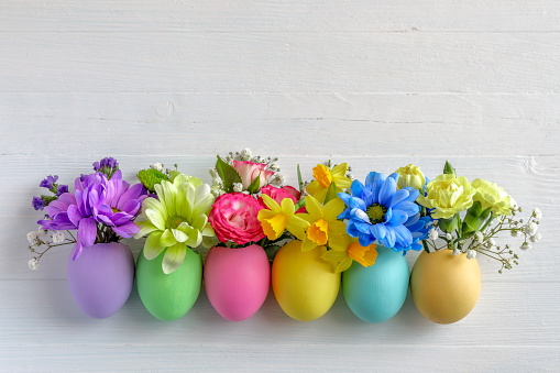 Easter home decoration. Egg shell with small yellow wildflowers on spring twigs  floral arrangement for spring Holiday