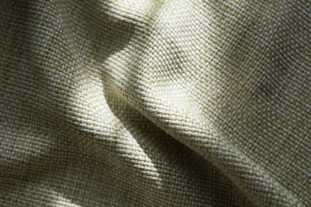 istock Close-up of a folded green synthetic fabric with a large thread 937282070