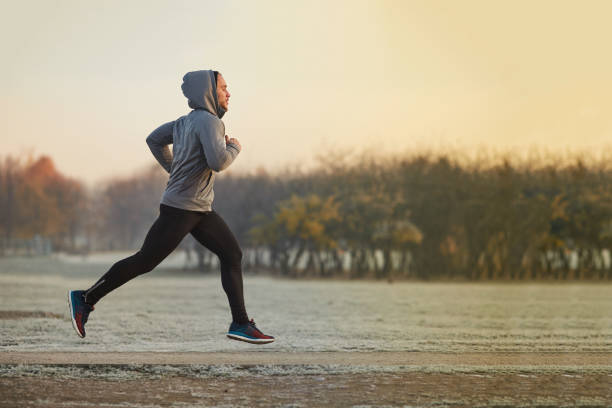 Young athletic man running at park during cold autumn morning Young athletic man running at park during cold autumn morning running motion stock pictures, royalty-free photos & images