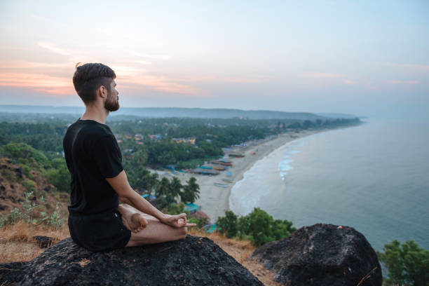 istock Healthy man practicing yoga under the beach at sunset. 937290550