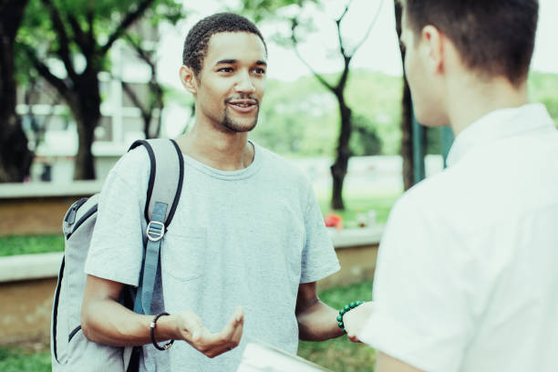 istock Smiling young student man taking to friend outdoor 937294692